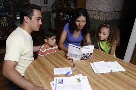 two adults and two children sitting around a wooden table with paperwork on it. interior